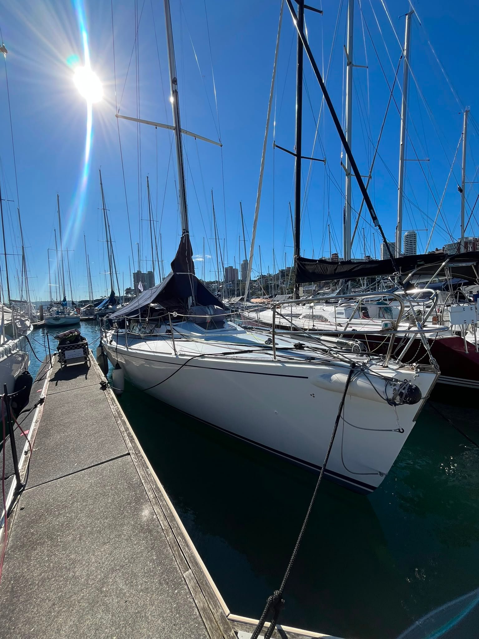 J130 with a white hull and dark boom tent and blue sky tied up in sydney after the yacht delivery