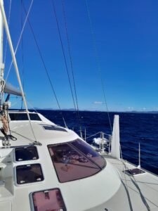 schionning 1600 on a yacht delivery with land in the back ground and blue sea that is calm
